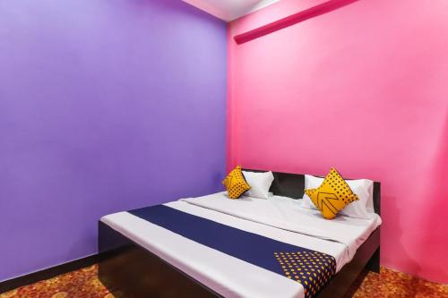 Schlafzimmer mit rosa und violetten Wänden und einem Bett in der Unterkunft OYO 78880 Rajdhani Hotel in Kākori