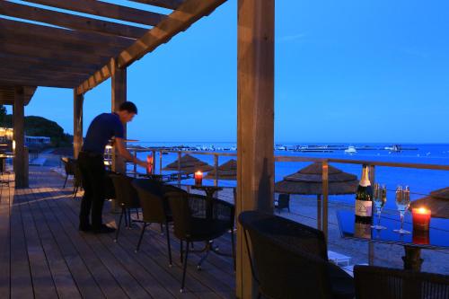 a man standing on a deck with a table with wine bottles at Le Pinarello in Sainte-Lucie de Porto-Vecchio