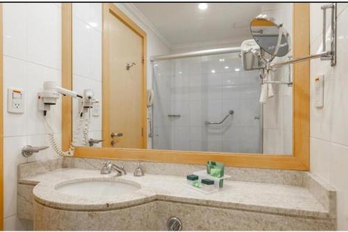 a bathroom with a sink and a mirror at Golden Flat's - Slaviero Guarulhos in Guarulhos