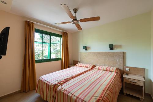 une chambre avec un lit et un ventilateur de plafond dans l'établissement Bungalows Cordial Sandy Golf, à Maspalomas