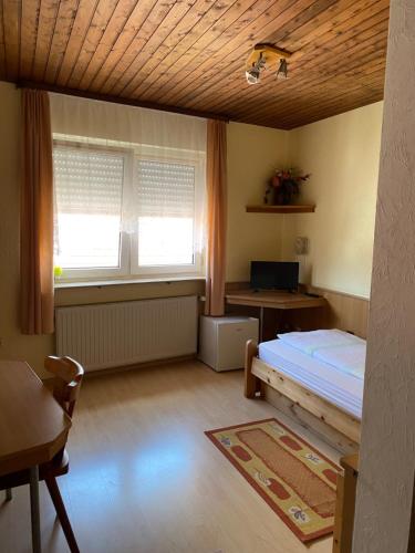 a bedroom with a bed and a desk and two windows at Landgasthaus zum Hirsch in Ramsen