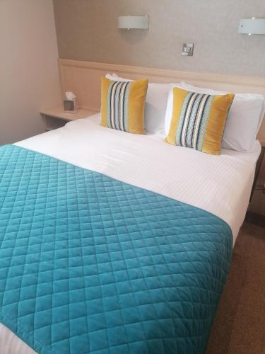 a large bed with yellow and blue sheets and pillows at The Lodge Hotel in Coleraine
