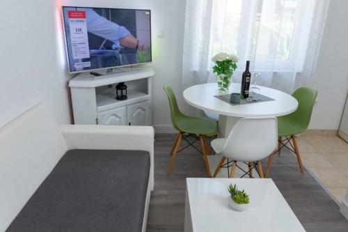 a living room with a white table and a tv at Apartments Pasalic in Kaštela