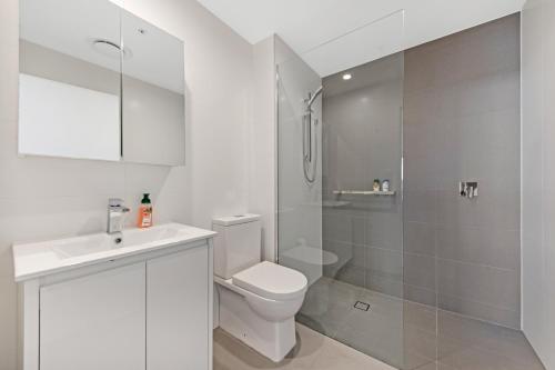 a white bathroom with a toilet and a shower at Fully equipped apartment in Rockdale in Sydney