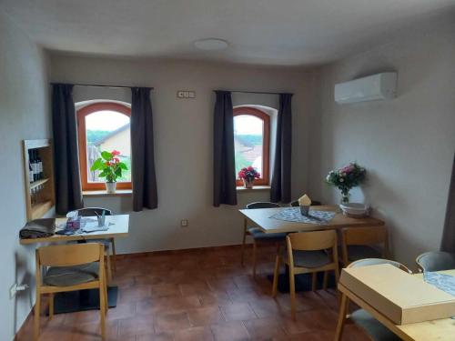 a living room with a table and chairs and two windows at Sklep Víno Strýček in Velké Bílovice