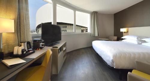 um quarto de hotel com uma cama e uma secretária com uma televisão em AC Hotel by Marriott Marseille Prado Vélodrome em Marselha