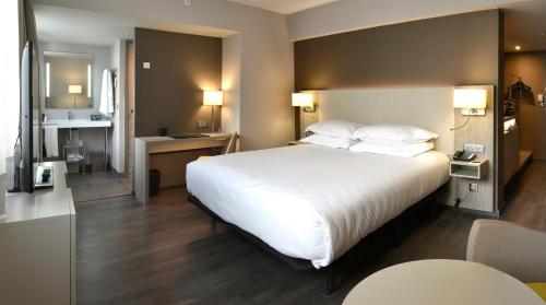 una habitación de hotel con una gran cama blanca y una cocina en AC Hotel by Marriott Marseille Prado Vélodrome en Marsella