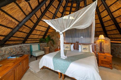 een slaapkamer met een hemelbed bij Hornbill Lodge in Kariba