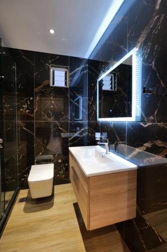 une salle de bain avec un lavabo, des toilettes et un miroir dans l'établissement Twins Villa, à Saranda