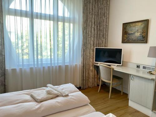 um quarto de hotel com uma cama e uma secretária com um computador em Villa Edda - Ferienzimmer 17 em Graal-Müritz