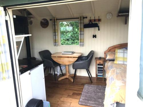 Idyllic Shepherds Hut glorious views to South Downs 'Perch' في يوكفيلد: غرفة مع طاولة وسرير في مقطورة