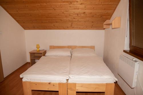 two beds in a room with a wooden ceiling at Apartmány Alma in Vyhne