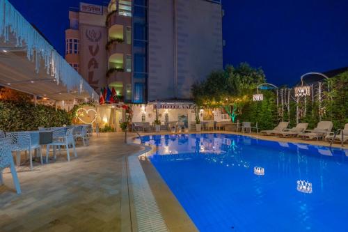 a swimming pool at night with tables and chairs at Hotel Valz in Velipojë