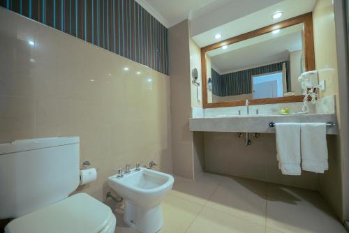 a bathroom with a toilet and a sink and a mirror at Condado Hotel Casino Paso de la Patria in Paso de la Patria
