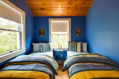 two beds in a room with blue walls and a window at Enchanting Retreat in Prospect Harbor in Prospect Harbor