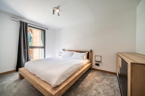 une chambre blanche avec un lit et une fenêtre dans l'établissement Elouera Les Gets - BY EMERALD STAY, aux Gets
