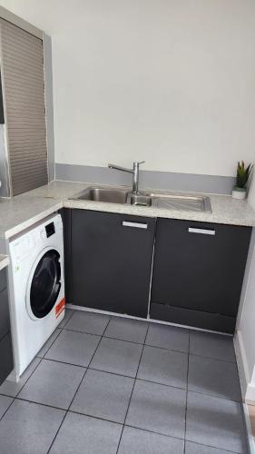 een keuken met een wastafel en een wasmachine bij Luxury 2 Bed Apartment EXCEL London in Londen