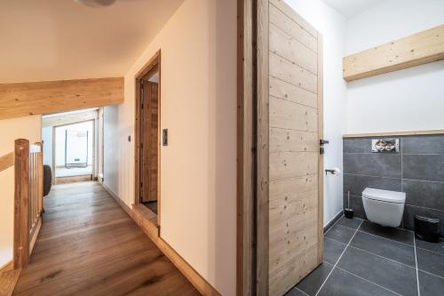 une salle de bain avec toilettes et porte en bois dans l'établissement Elouera Les Gets - BY EMERALD STAY, aux Gets