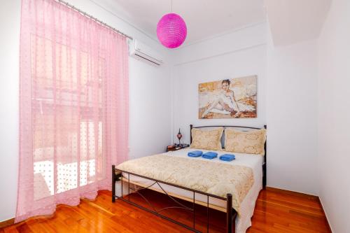 a bedroom with a bed and a window with pink curtains at Koukaki Apartment in Athens