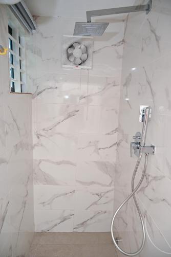 a bathroom with a shower with white marble walls at Lokko Serene in Accra