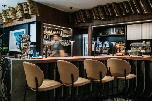 a bar with chairs and a person in the background at Mercure Brest Centre Port in Brest