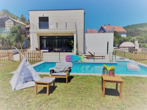 un patio trasero con una piscina con 2 sillas y una mesa en Casa con piscina en Liméns, en Hío