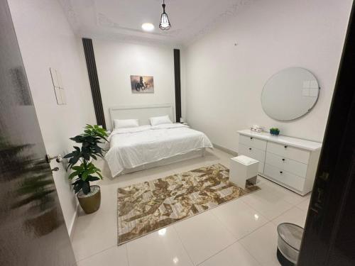 a white bedroom with a bed and a mirror at Smart Entry Apartment w Pvt Entrance in Riyadh