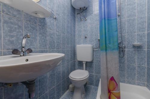 a blue tiled bathroom with a sink and a toilet at Apartment Radojka in Bol