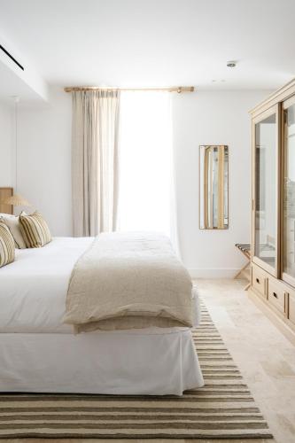 a white bedroom with a large bed and a window at Le Couvent des Minimes, un Hôtel & Spa L'Occitane en Provence in Mane