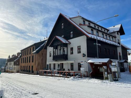 a large building on the side of a snow covered street at Kvildahotel in Kvilda