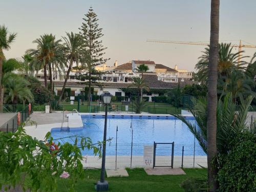 una gran piscina con un aro de baloncesto y palmeras en Vacaciones en Marbella, en Marbella