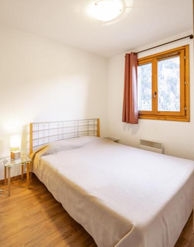 un lit blanc dans une chambre avec une fenêtre dans l'établissement Hameau 8 102 - SPA & PISCINE appartement 4 pers, à Orelle
