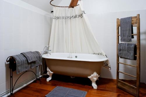 a bath tub in a bathroom with a curtain at Ferme de l'Abbaye St-Feuillien in Roeulx