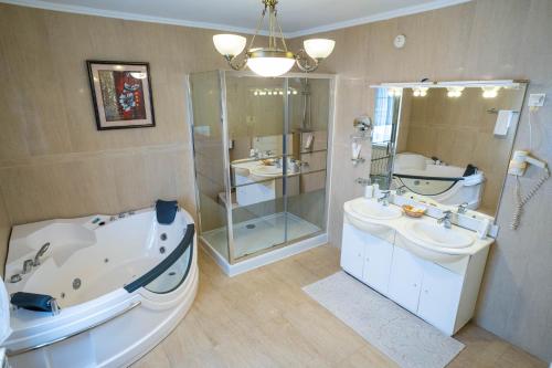 a bathroom with a tub and two sinks and a shower at Villa Alice in Suceava