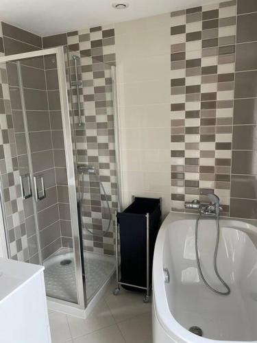 a bathroom with a tub and a shower and a tub at Maison spacieuse Pêni-Pênant in Pirou