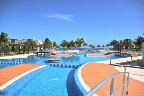 a large swimming pool with blue water and palm trees at Luxury Condos at Mareazul Beachfront Complex with Resort-Style Amenities in Playa del Carmen
