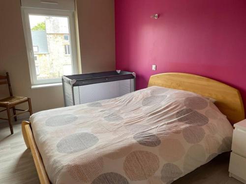 a bedroom with a bed and a pink wall at Maison spacieuse Pêni-Pênant in Pirou