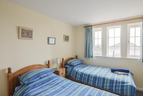 two beds in a bedroom with blue and white sheets at 5 Buckfields in Lyme Regis