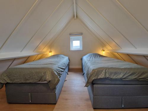 a attic bedroom with two beds and a window at Premium Holidays - modern vacation home in a vacation park in Nieuwpoort in Nieuwpoort