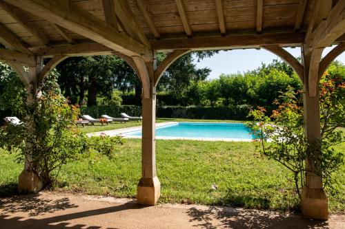 a wooden pergola with a pool in a yard at Château Gautoul in Puy-lʼÉvêque