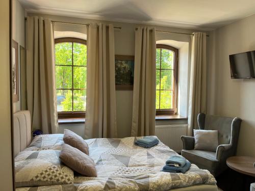 um quarto com uma cama, uma cadeira e janelas em Spalskie Pokoje Gościnne em Spala