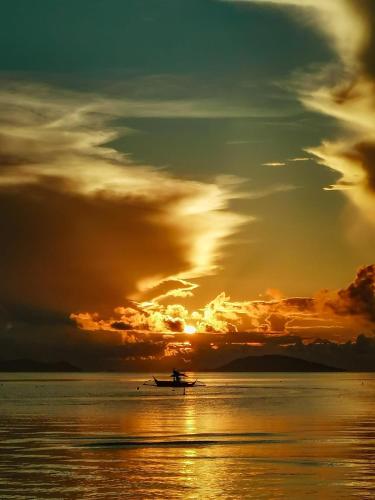 a boat in the water with a sunset at JCAH BEACH HOUSE free WiFi in Araceli