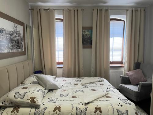 a bedroom with a bed and a chair and windows at Spalskie Pokoje Gościnne in Spała
