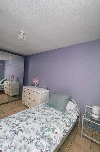 une chambre avec un lit et un mur bleu dans l'établissement La Violette ONLY WOMEN femmes uniquement, à Vénissieux