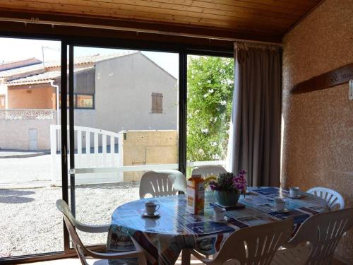 une table avec des chaises blanches, une table bleue et une fenêtre dans l'établissement Charmante Villa 3 Chambres à 800m de la Plage avec Véranda et Terrasse, Quartier Calme - FR-1-229D-235, à Fleury