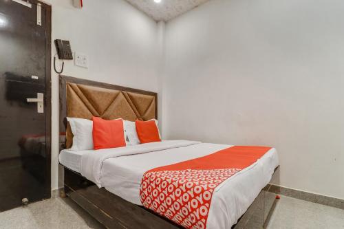 a bedroom with a bed with orange and white pillows at Hotel O Sun View in Ludhiana