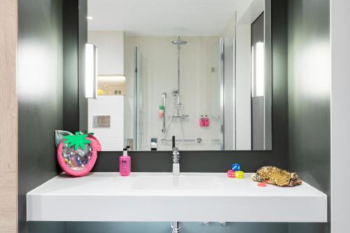 een badkamer met een witte wastafel en een spiegel bij Moxy Dresden Neustadt in Dresden