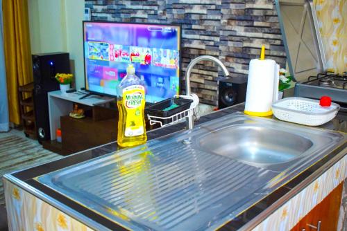 Casabella Apartment - Pristine Homes,Tom Mboya في كيزيمو: منضدة مطبخ مع مغسلة وتلفزيون