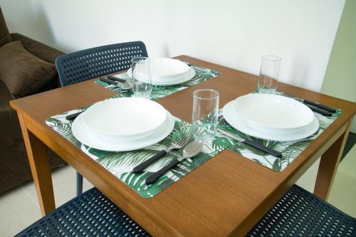 a wooden table with plates and silverware on it at Porto Star Prime By AFT in Porto De Galinhas