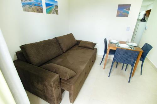 a living room with a brown couch and a table at Porto Star Prime By AFT in Porto De Galinhas